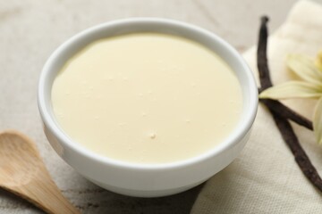 Tasty condensed milk, vanilla pods, flower and spoon on light grey table, closeup