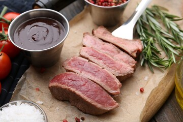 Delicious sliced beef tenderloin with different degrees of doneness, sauce and spices on table, closeup
