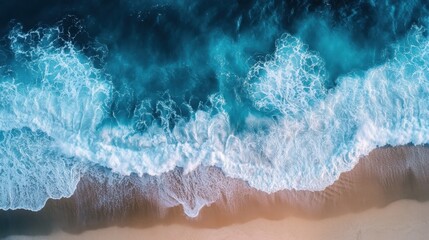 Aerial view of turquoise ocean waves crashing onto a golden sand beach creating a dynamic and refreshing coastal scene in a natural light setting