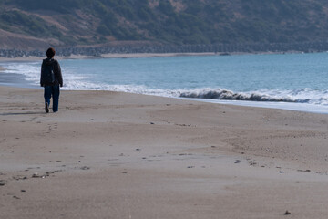 砂浜を歩く人の後ろ姿