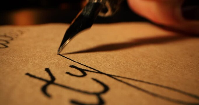 closeup of hand writing letter with vintage quill pen and ink on old parchment paper