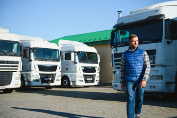 Freight transportation. A handsome truck driver stands on the background of a truck in the parking...