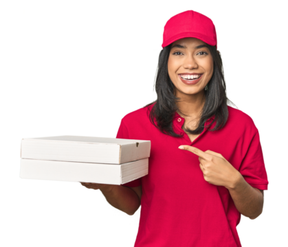 Latina delivering pizza, studio setup smiling and pointing aside, showing something at blank space.