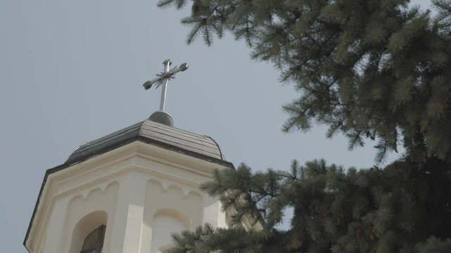 A Church Tower proudly displays a Cross with a Tree Background for scenic beauty and significance