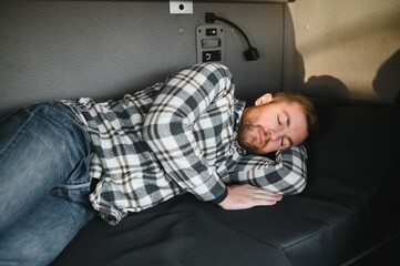 Truck driver sleeping in his cabin after working long routes overtime. Sleepy trucker taking a nap...