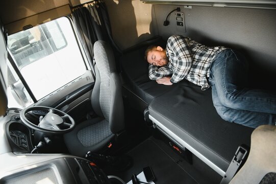 Truck driver sleeping in his cabin after working long routes overtime. Sleepy trucker taking a nap on a bed inside truck transporter. Lack of sleep