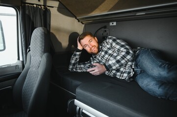 A trucker in the cab, lying in the truck bed, scrolling on his phone during his spare time