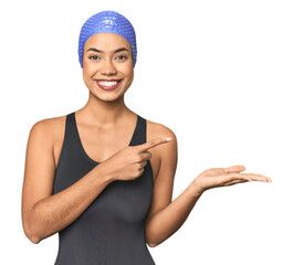 Pro Latina swimmer in studio gear excited holding a copy space on palm.