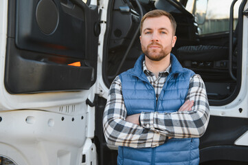 Happy truck driver standing with arms crossed in front of his truck