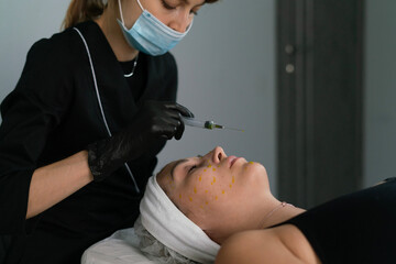 A skilled cosmetologist applies a face peeling treatment using a syringe on a client's skin in a contemporary skincare clinic, focusing on rejuvenation and renewal