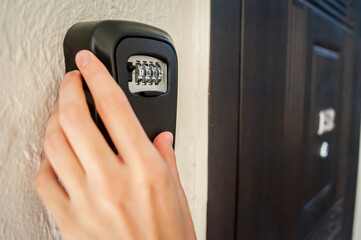 Safe entry of combination lock on wall box for storing keys in residential building. Keyless access to apartment