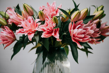 A vase full of pink flowers sits on a table. The flowers are arranged in a way that they are all facing the same direction, creating a sense of harmony and balance. The vase itself is clear