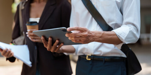 Sustainability and Technology. Two professionals discussing sustainable practices using a tablet in an outdoor setting.