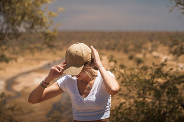 Young blonde woman adjusting her hat while visiting tarangire national park in tanzania, africa