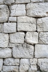 Fototapeta premium Weathered stone wall texture background in neutral tones showcasing aged construction and natural cracks creating a vintage and rustic architectural element