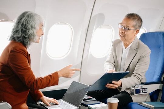 Business meeting in airplane, asian Mature businessman in private jet is talking with Mature female colleague and documents, business people flying in airplane