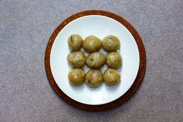 Cilok is a traditional food from Indonesia, made from tapioca, round shape, chewy textured. White plate on the gray gravel. Selective focus