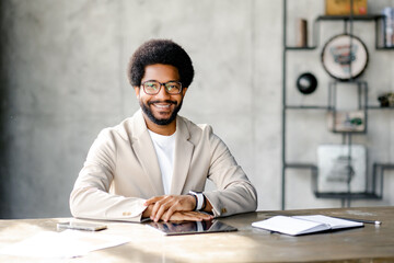 Brazilian businessman with genial smile radiates as he sits at a desk, representing the seamless...