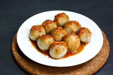 Cilok, served in white plate with peanut sauce. Popular snack from Indonesia made by tapioca flour. isolated black background. Selective focus.