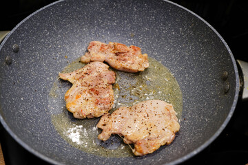 Chicken frying in a frying pan on a cooker