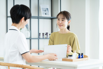 エステサロンで肌の相談をする若い女性