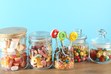 Candy bar. Many different sweets on wooden table against light blue background, closeup. Space for text