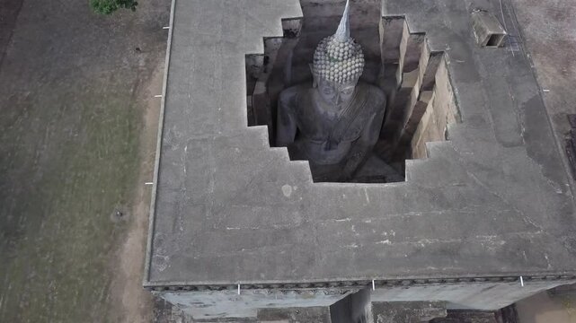 Aerial,ascending over the roof of Wat Si Chum Buddha Statue at Sukhothai,details of the statue from the top inside the building.