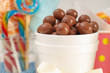 Candy bar. Chocolate sweets in paper cup on blurred background, closeup