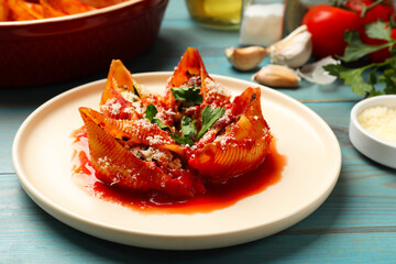 Delicious conchiglie pasta with ricotta cheese, tomato sauce and parsley on light blue wooden table, closeup