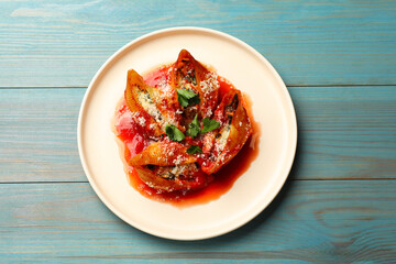 Delicious conchiglie pasta with ricotta cheese, tomato sauce and parsley on light blue wooden table, top view