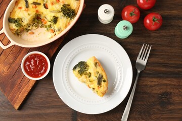 Tasty vegetable casserole served with sauce and spices on wooden table, flat lay