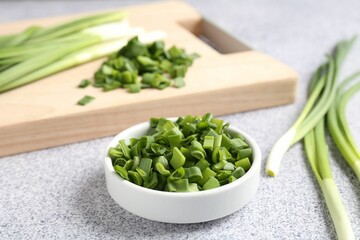 Whole and cut fresh green onions on light grey table, closeup