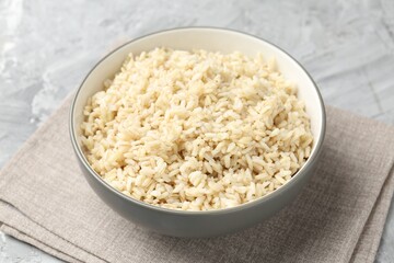Delicious brown rice served on grey textured table, closeup