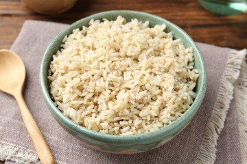 Delicious brown rice served on wooden table, closeup