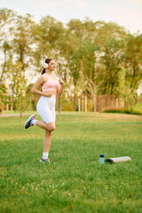 Joyful young woman enjoying a morning jog in a vibrant park surrounded by nature