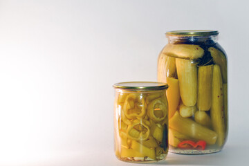 Vegetable marinade on white background. Canned sour vegetables in glass jars. Pickled vegetables in a jar - cucumbers, tomatoes, peppers, okra.