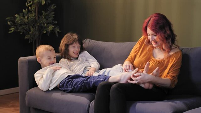 Mother tickling children's feet on sofa