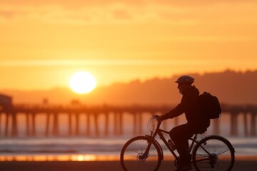 Obraz premium Cyclist enjoying a sunset ride along the beach with a pier in the background