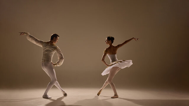 Ballet duet flows together, arms extended, legs poised, every movement controlled yet weightless, captured in glowing light. Concept of rhythm, emotion, beauty, poise, artistic connection, performance