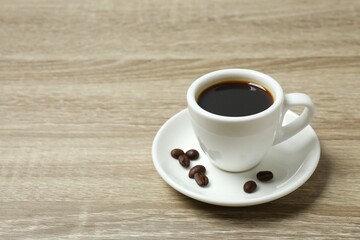 Cup of coffee with coffee beans on wooden background