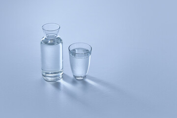 Photo of clear glass carafe and matching glass, both filled with transparent water, against light...
