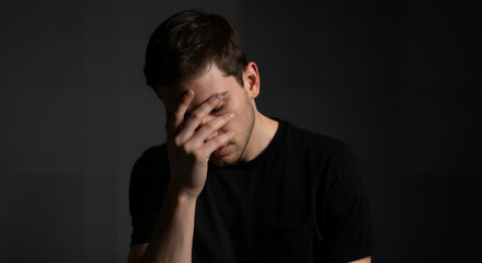 A man with averted eyes and protective posture reveals deep shame while trying to hide from judgment.
