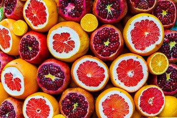 Close-up of fresh citrus fruits and pomegranates, sliced open to reveal vibrant textures. A...