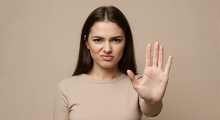 A woman with a repulsed expression and defensive gesture demonstrates strong disgust toward something unpleasant.