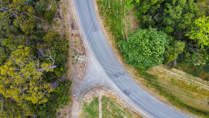A winding road with a power line running above it, seen from above