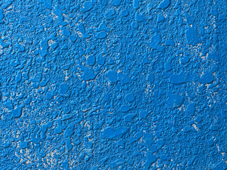 Close-up view of a textured surface with varying shades and patterns of blue, and irregular shapes and raised areas. The rough texture and scattered design create an dynamic abstract visual effect.