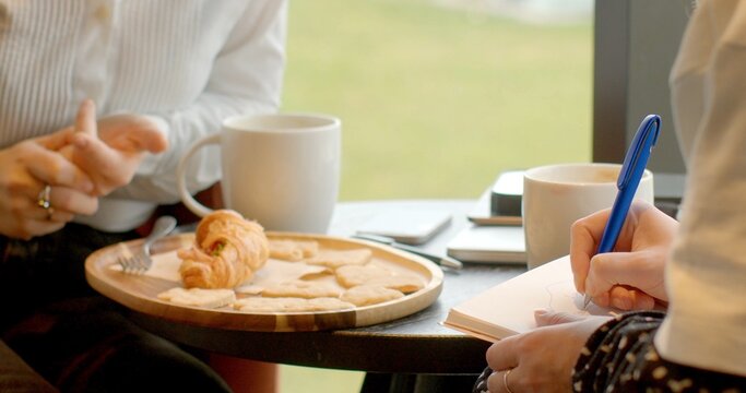 Two individuals sharing coffee and pastries at a table in a caf background