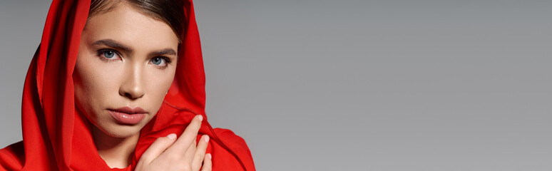 Beautiful young woman in a striking red hooded outfit showcasing modern fashion elegance