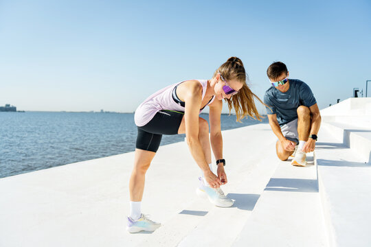 Athletes preparing for a run on a sunny day by the waterfront with clear blue skies