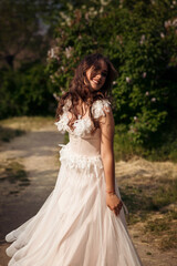Stunning bride gracefully poses in a spring park, among blossoming trees. exuding elegance,